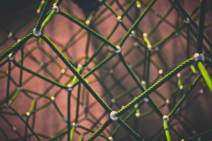 A meshwork of green ropes against a red background